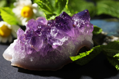 Beautiful amethyst and camomile flowers on table, closeup. Healing crystal