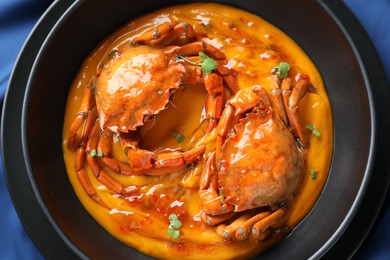 Photo of Delicious boiled crabs with sauce in bowl on table, top view