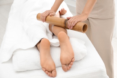 Woman having massage with bamboo stick in wellness center