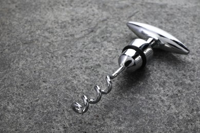 One metal corkscrew on grey textured table, closeup. Space for text