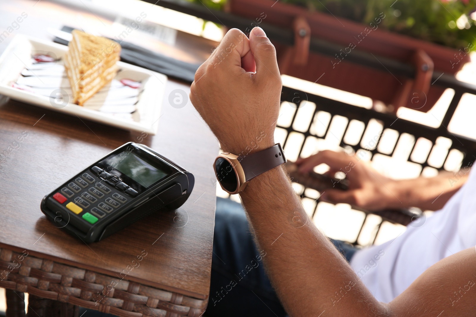 Photo of Man making payment with smart watch in cafe, closeup