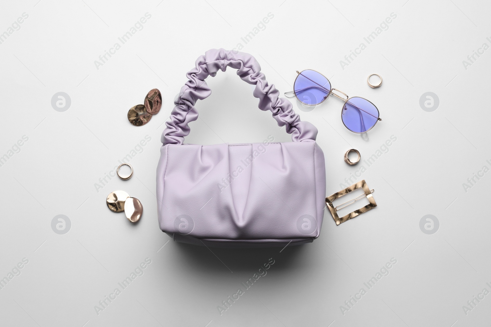 Photo of Stylish woman's bag, sunglasses and bijouterie on light background, flat lay