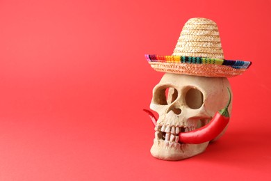 Photo of Human scull with Mexican sombrero hat and hot chili pepper on red background. Space for text