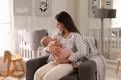 Photo of Young woman with her little baby in armchair at home