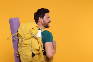 Photo of Man with backpack and mat on orange background, space for text. Active tourism