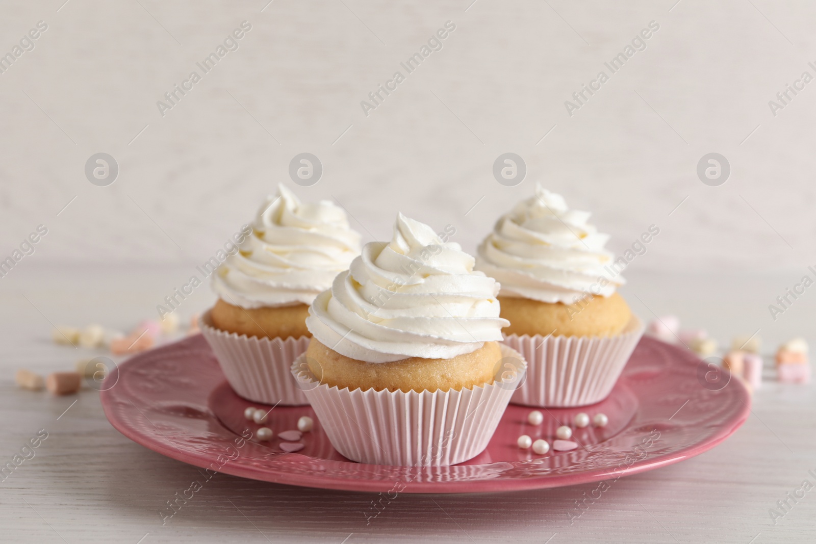 Photo of Delicious cupcakes with cream on white wooden table