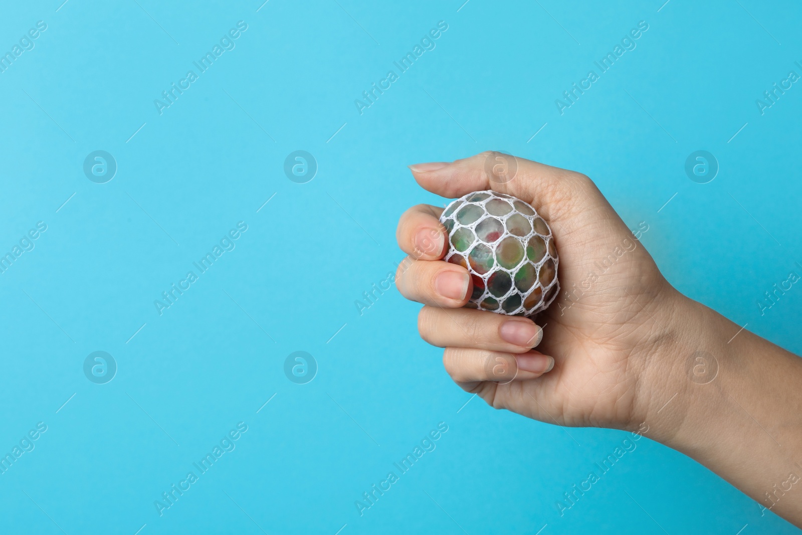 Photo of Woman holding colorful slime on blue background, closeup. Antistress toy