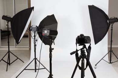 Tripod with camera and professional lighting equipment in photo studio