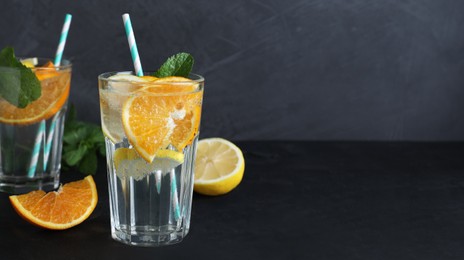 Tasty refreshing soda drink with lemon and orange slices on black table. Banner design with space for text