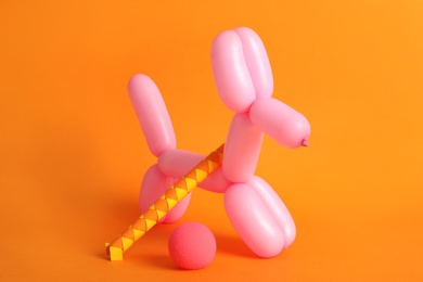 Photo of Dog figure made of modelling balloon and chinese finger trap on orange background