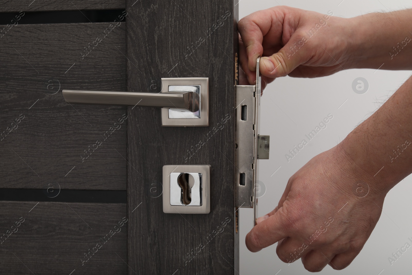 Photo of Handyman changing door handleset indoors, closeup view