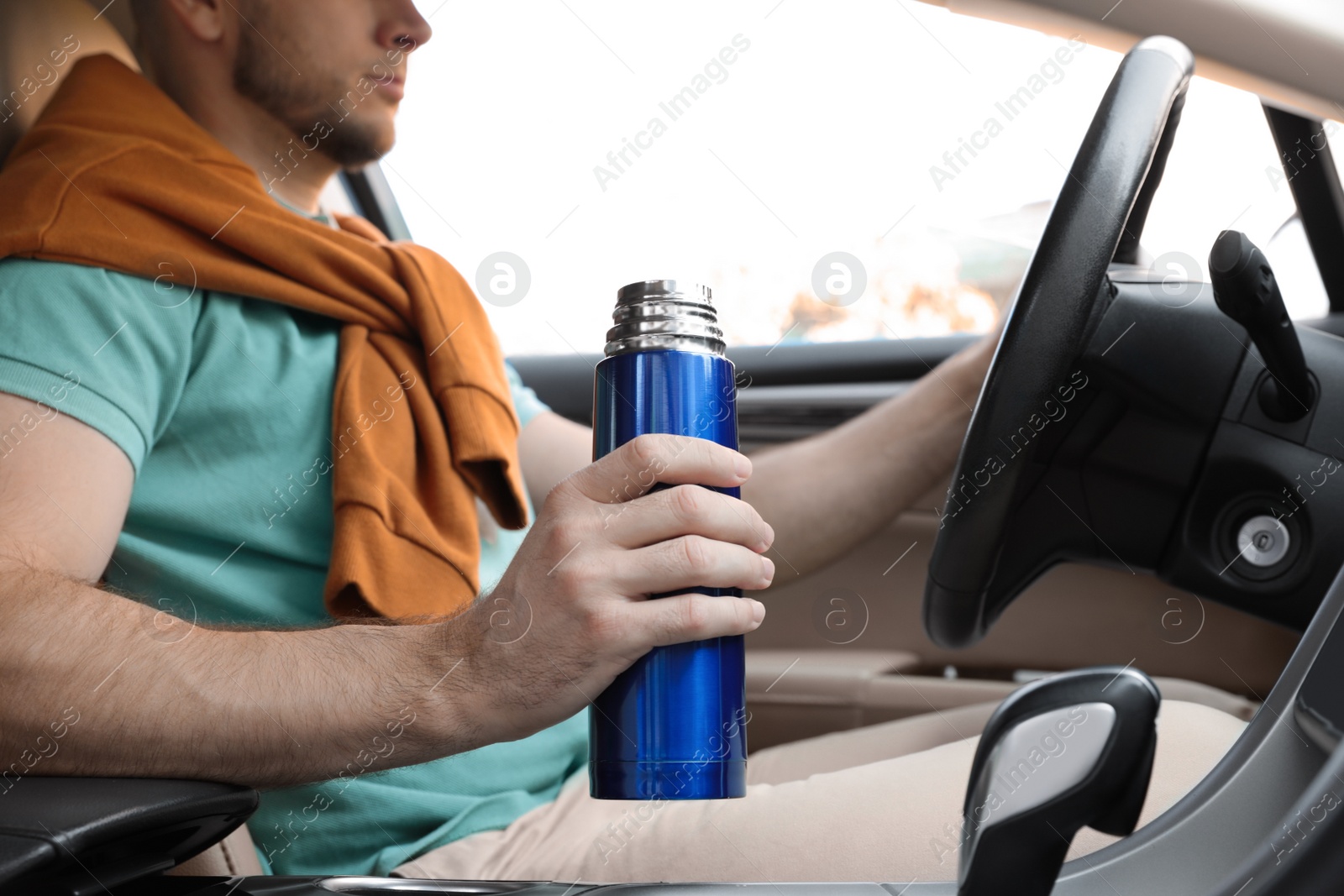 Photo of Man with thermos driving car, closeup view