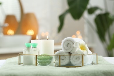 Composition with different spa products and burning candles on table indoors