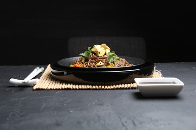 Photo of Stir-fry. Tasty noodles with meat and vegetables served on dark textured table