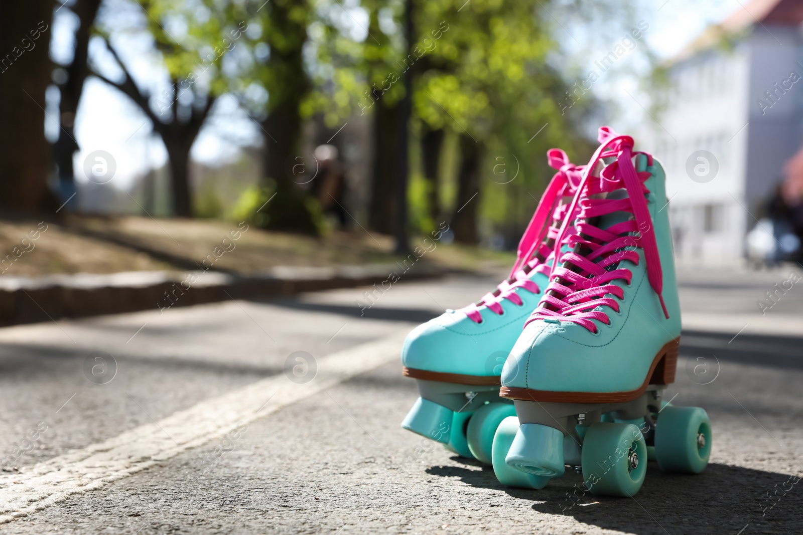 Photo of Stylish pink roller skates outdoors on sunny day. Space for text