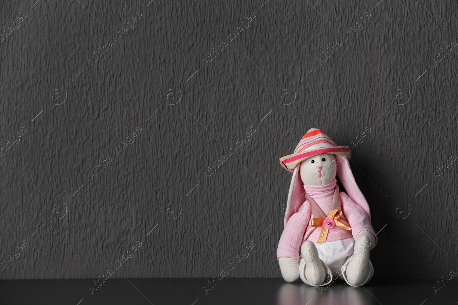 Photo of Abandoned toy bunny on table against gray background. Time to visit child psychologist