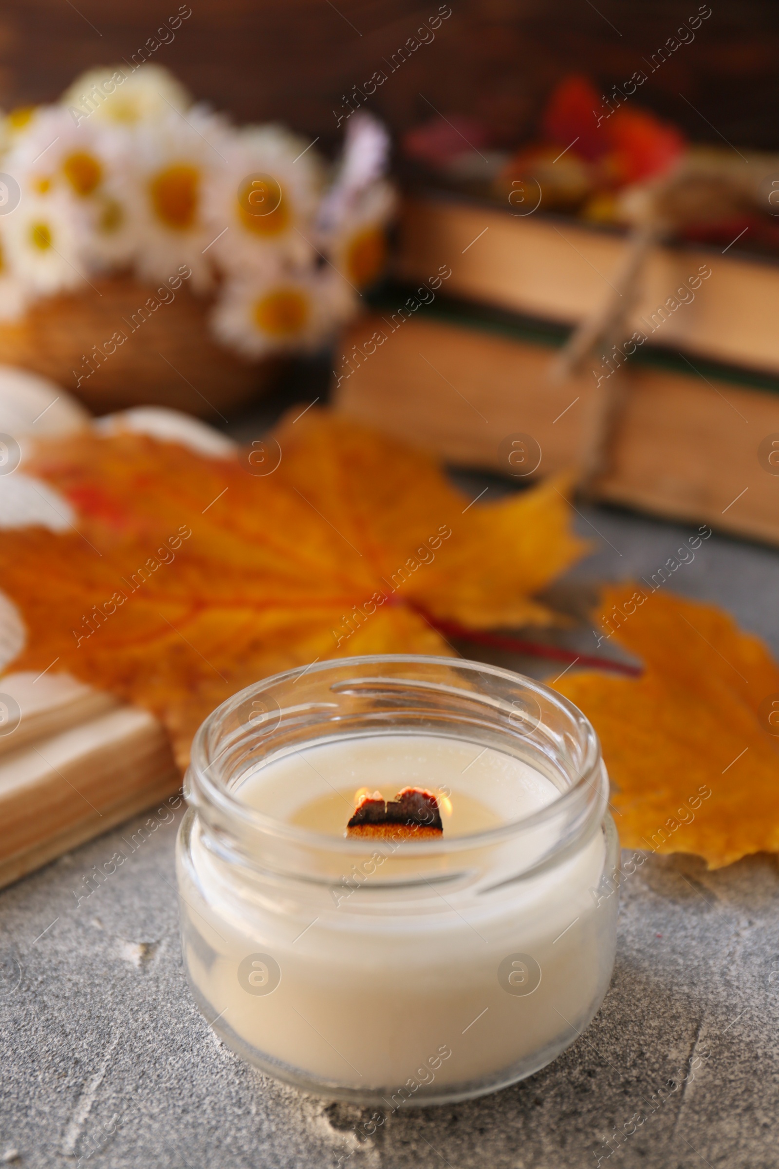 Photo of Burning scented candle on light gray textured table, space for text