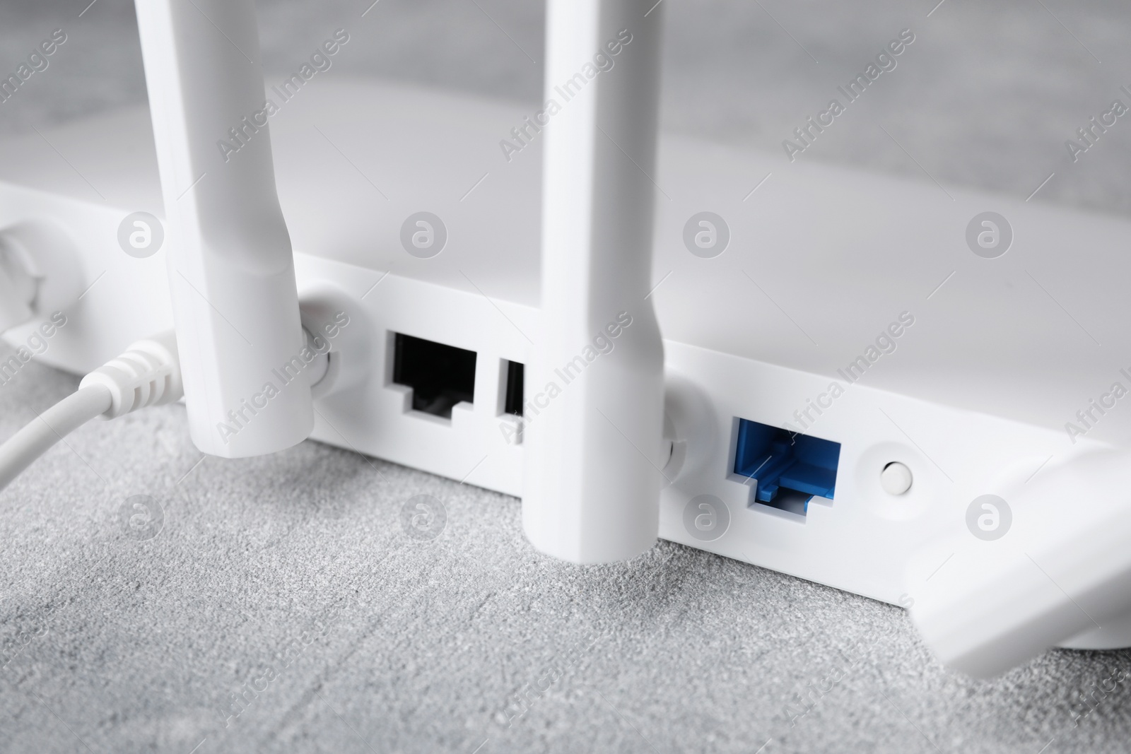 Photo of New modern Wi-Fi router on grey table, closeup