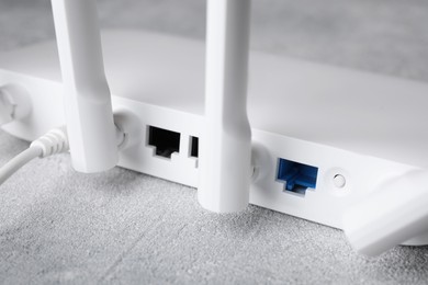 Photo of New modern Wi-Fi router on grey table, closeup
