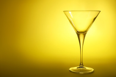 Photo of Elegant empty martini glass on yellow background. Space for text