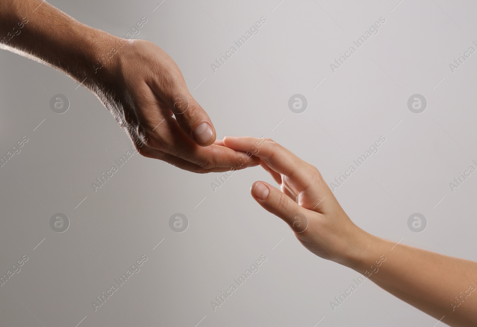 Photo of Man reaching for woman's hand on grey background, closeup. Help and support concept