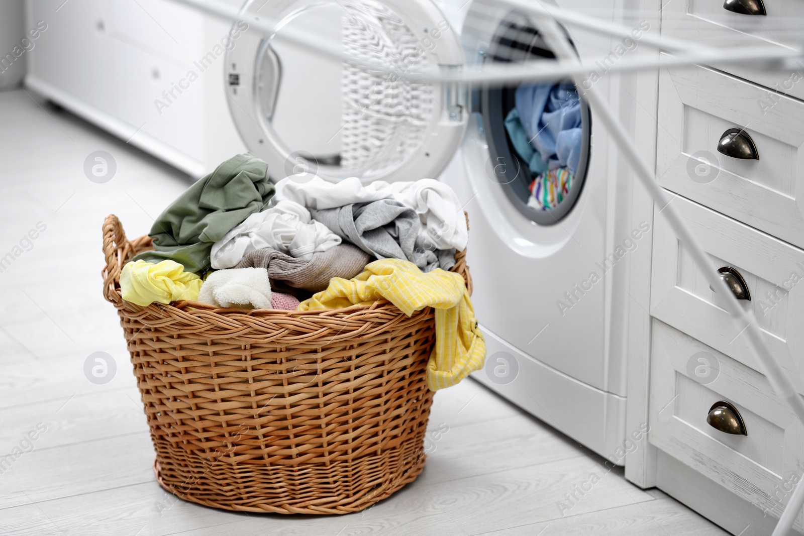 Photo of Wicker basket with dirty laundry on floor indoors