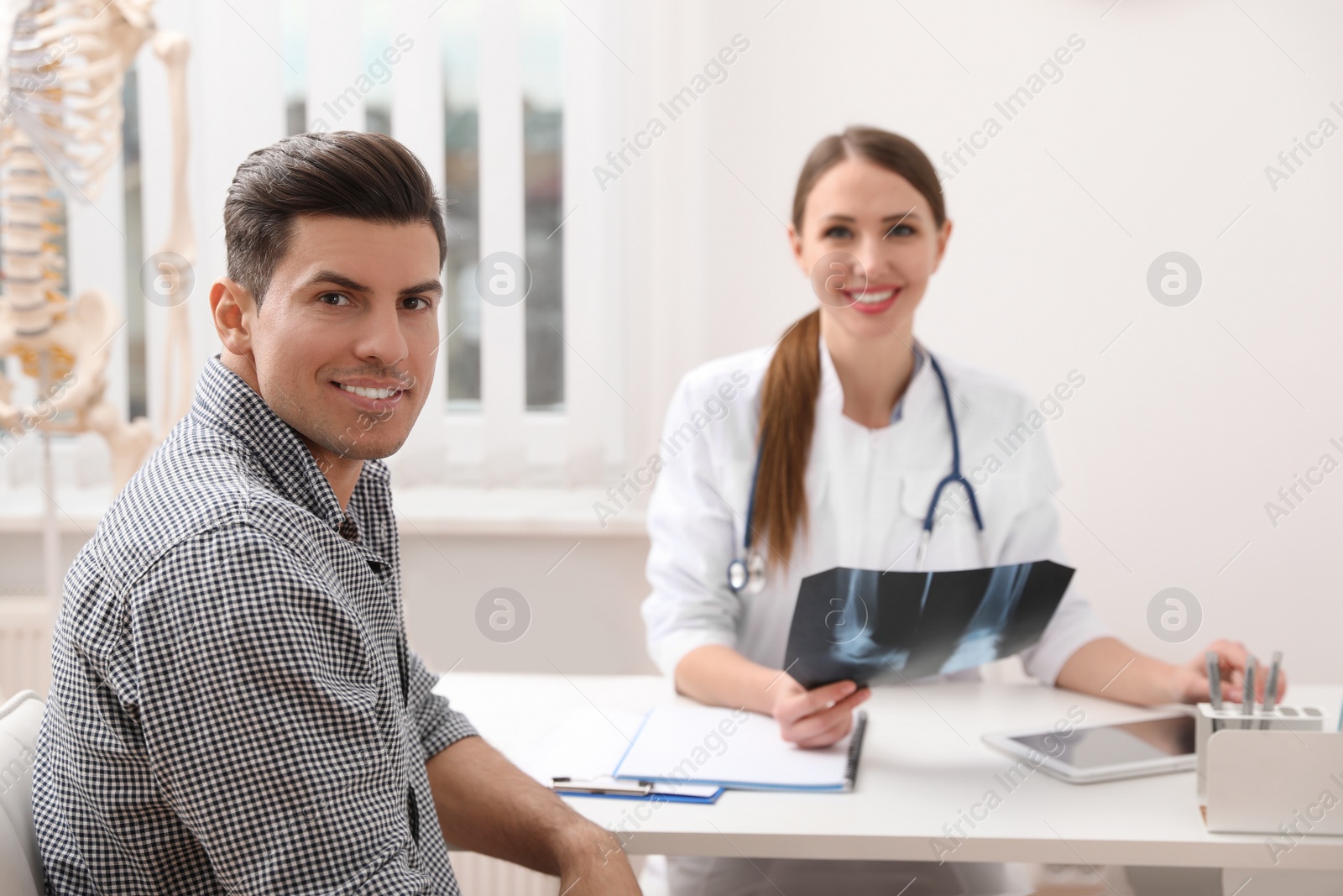 Photo of Orthopedist showing X-ray picture to patient at table in clinic
