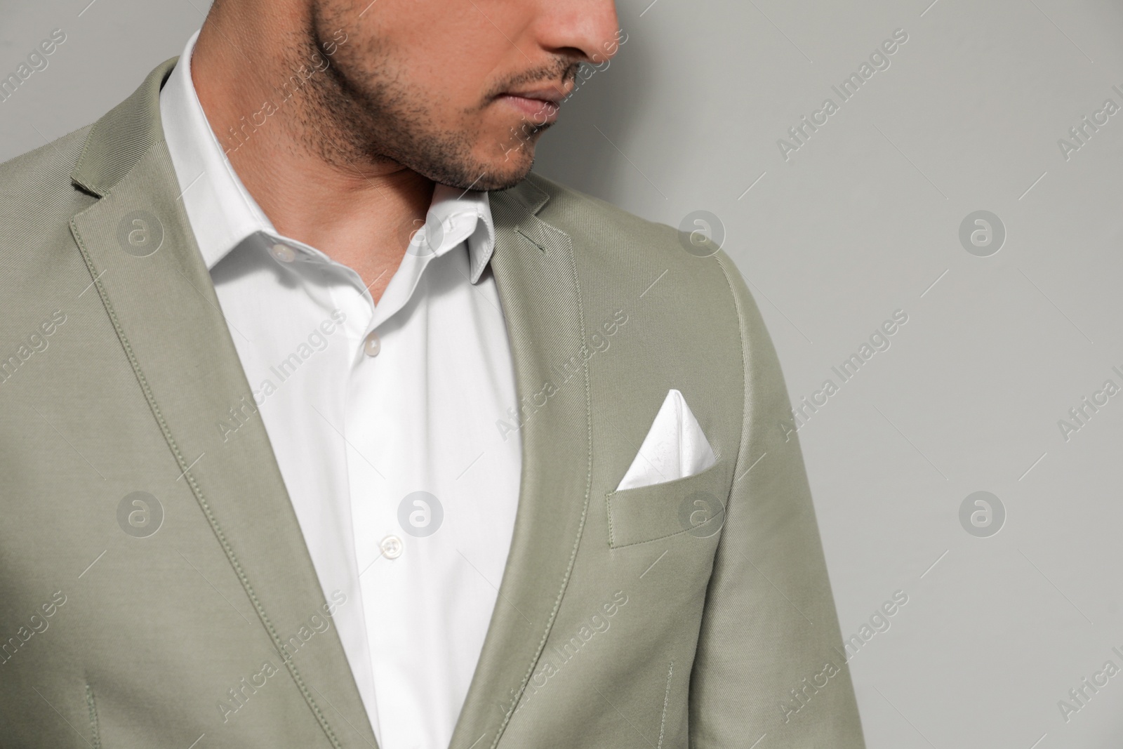 Photo of Man with handkerchief in breast pocket of his suit on grey background, closeup