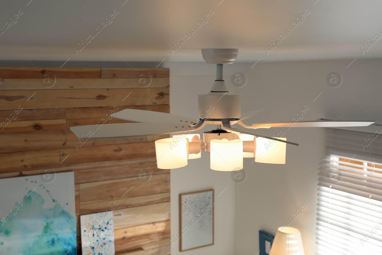 Photo of Modern ceiling fan with lamps in room