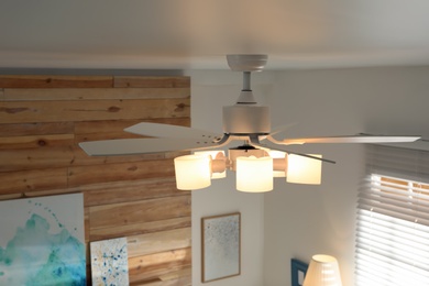 Modern ceiling fan with lamps in room