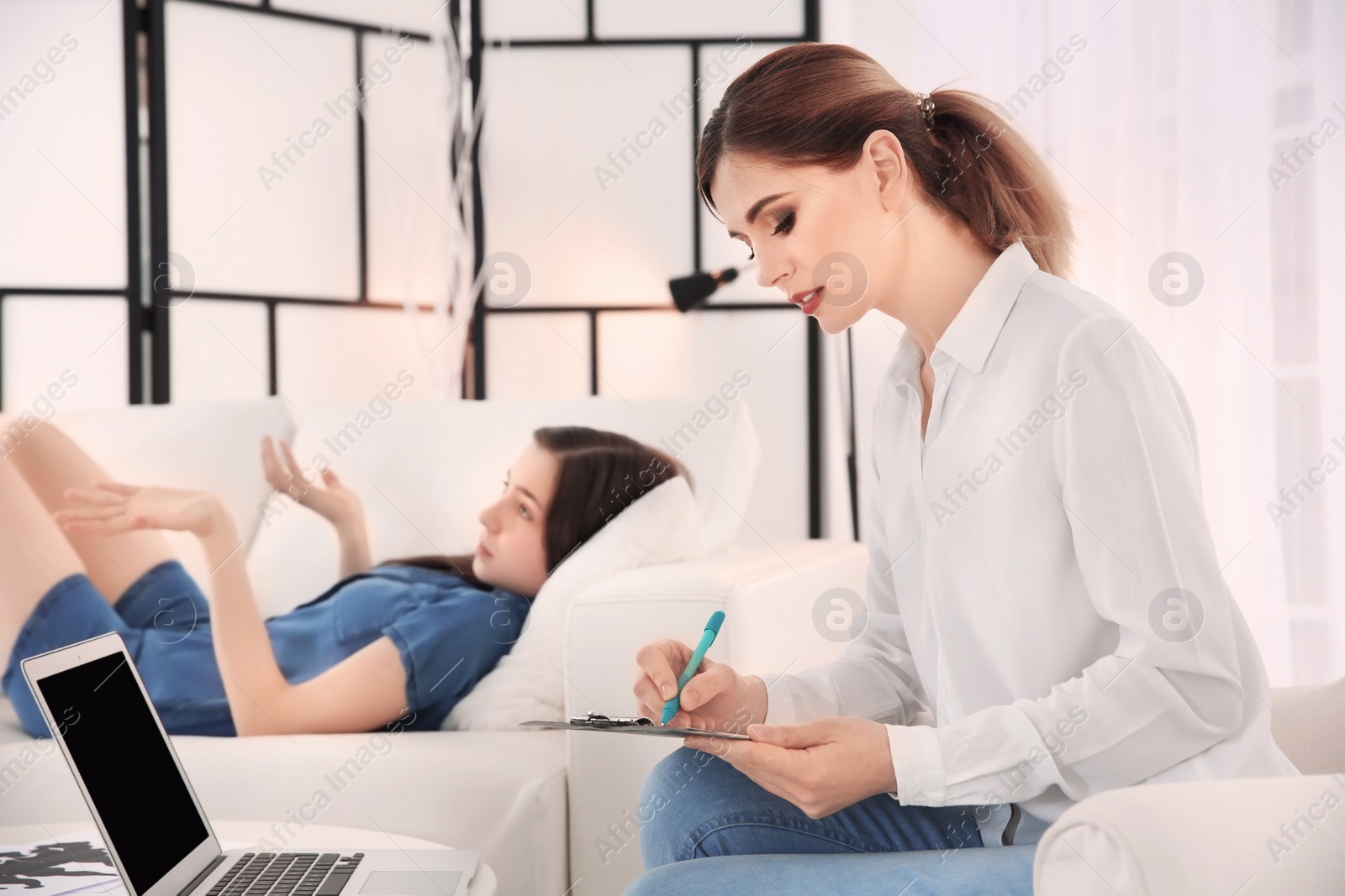 Photo of Female psychologist working with teenager girl in office