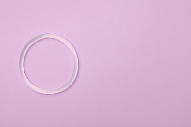 Diaphragm vaginal contraceptive ring on lilac background, top view. Space for text