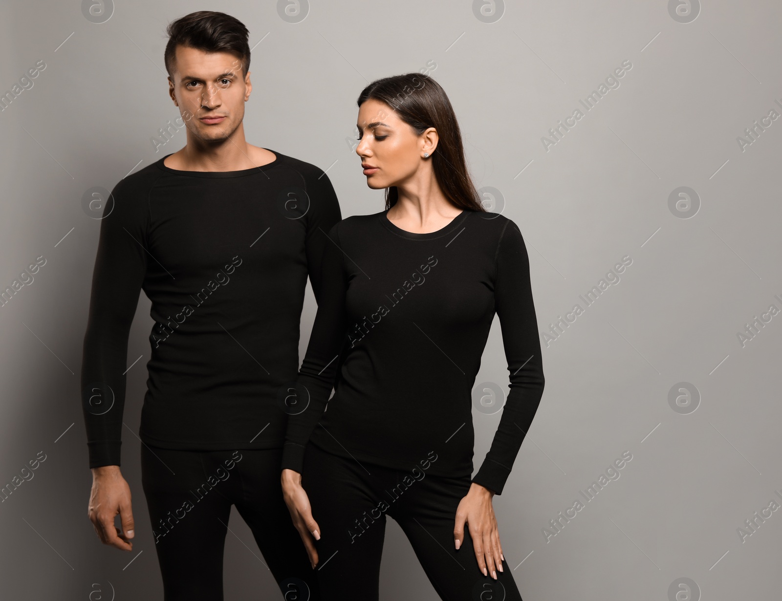 Photo of Couple wearing thermal underwear on grey background. Space for text