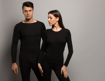 Photo of Couple wearing thermal underwear on grey background. Space for text