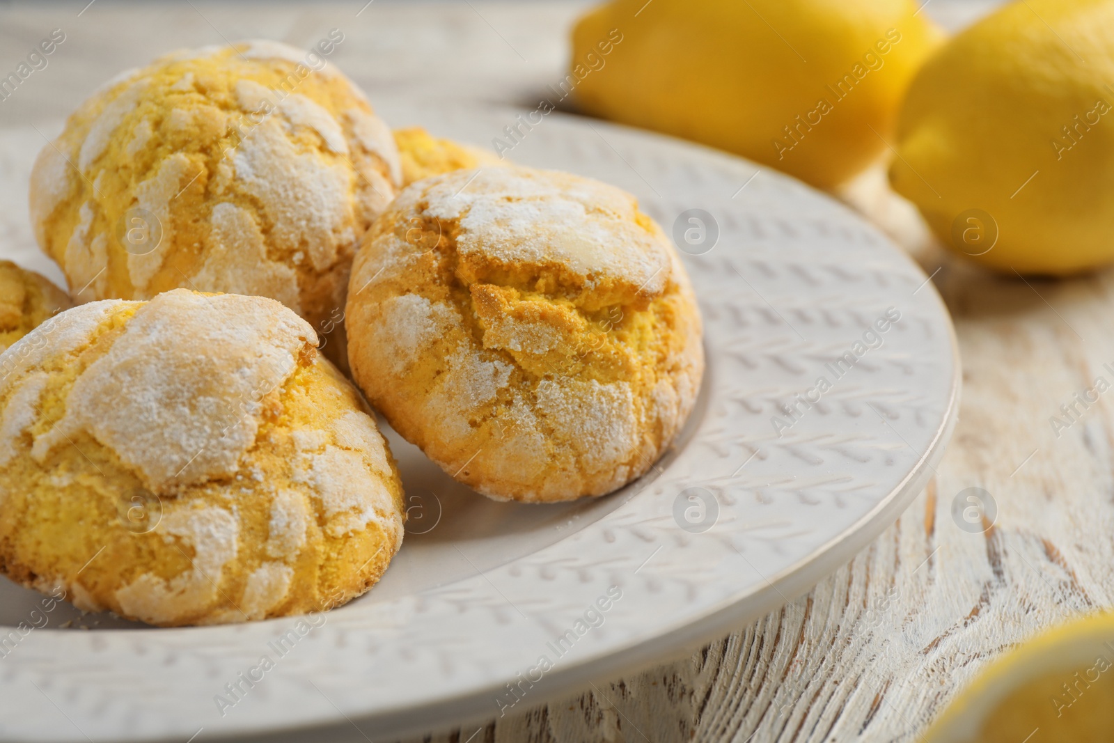 Photo of Delicious lemon cookies and citrus fruits on white wooden table, closeup