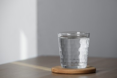 Glass of pure water on wooden table indoors, space for text