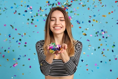 Happy woman and falling confetti on light blue background