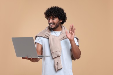 Smiling man having video call via laptop on beige background. Space for text