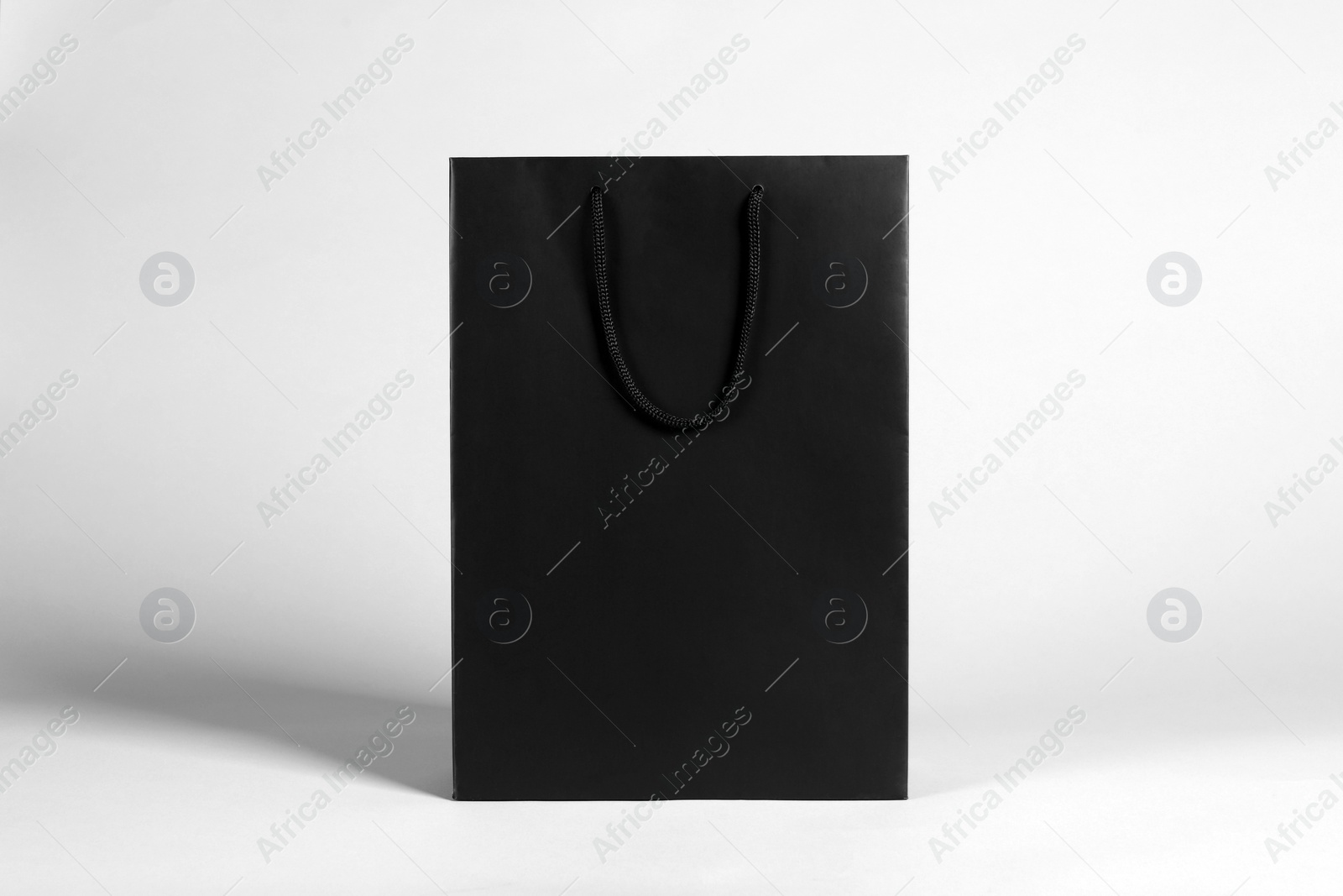 Photo of One black paper shopping bag on grey background