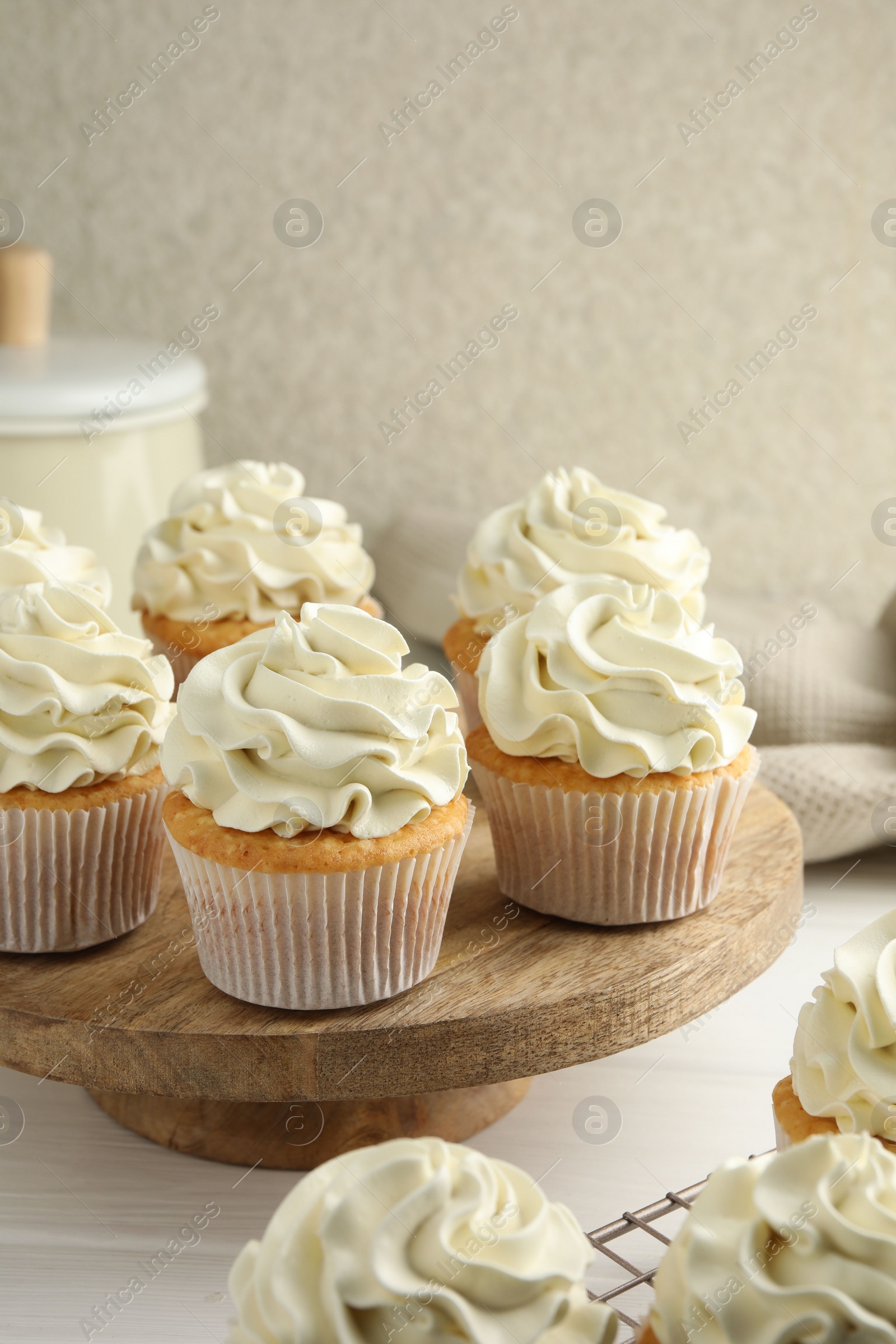 Photo of Tasty vanilla cupcakes with cream on white wooden table