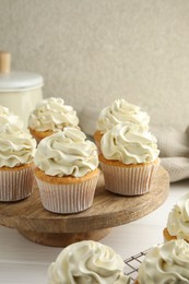 Photo of Tasty vanilla cupcakes with cream on white wooden table