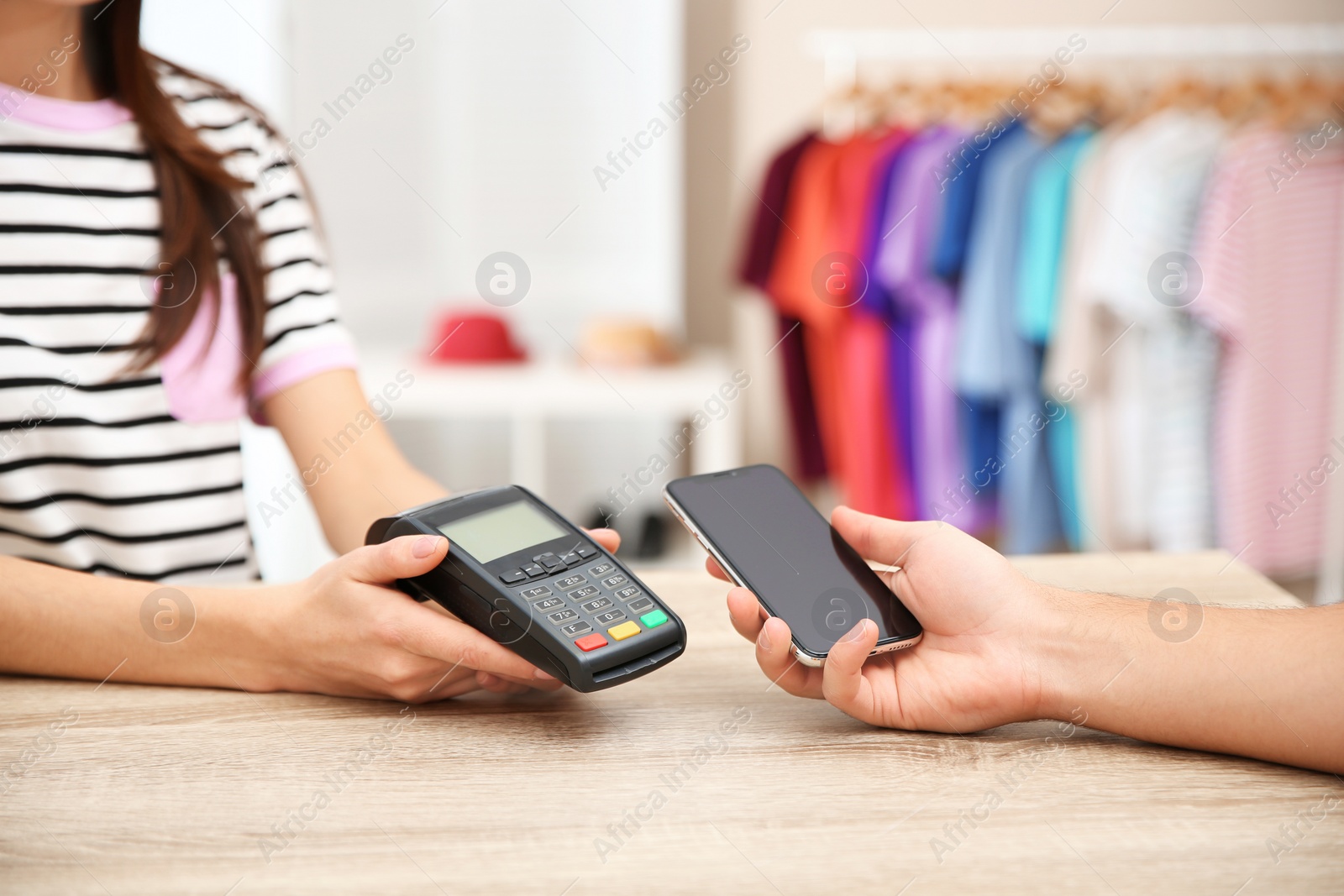 Photo of Man using payment terminal with smartphone in shop, closeup. Space for text