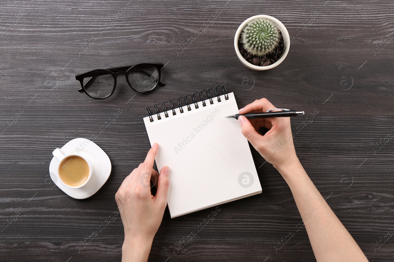 Photo of Woman with notebook and pen at grey wooden table, top view. Space for text