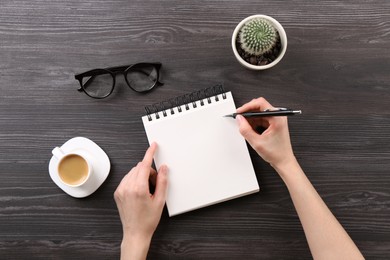 Woman with notebook and pen at grey wooden table, top view. Space for text