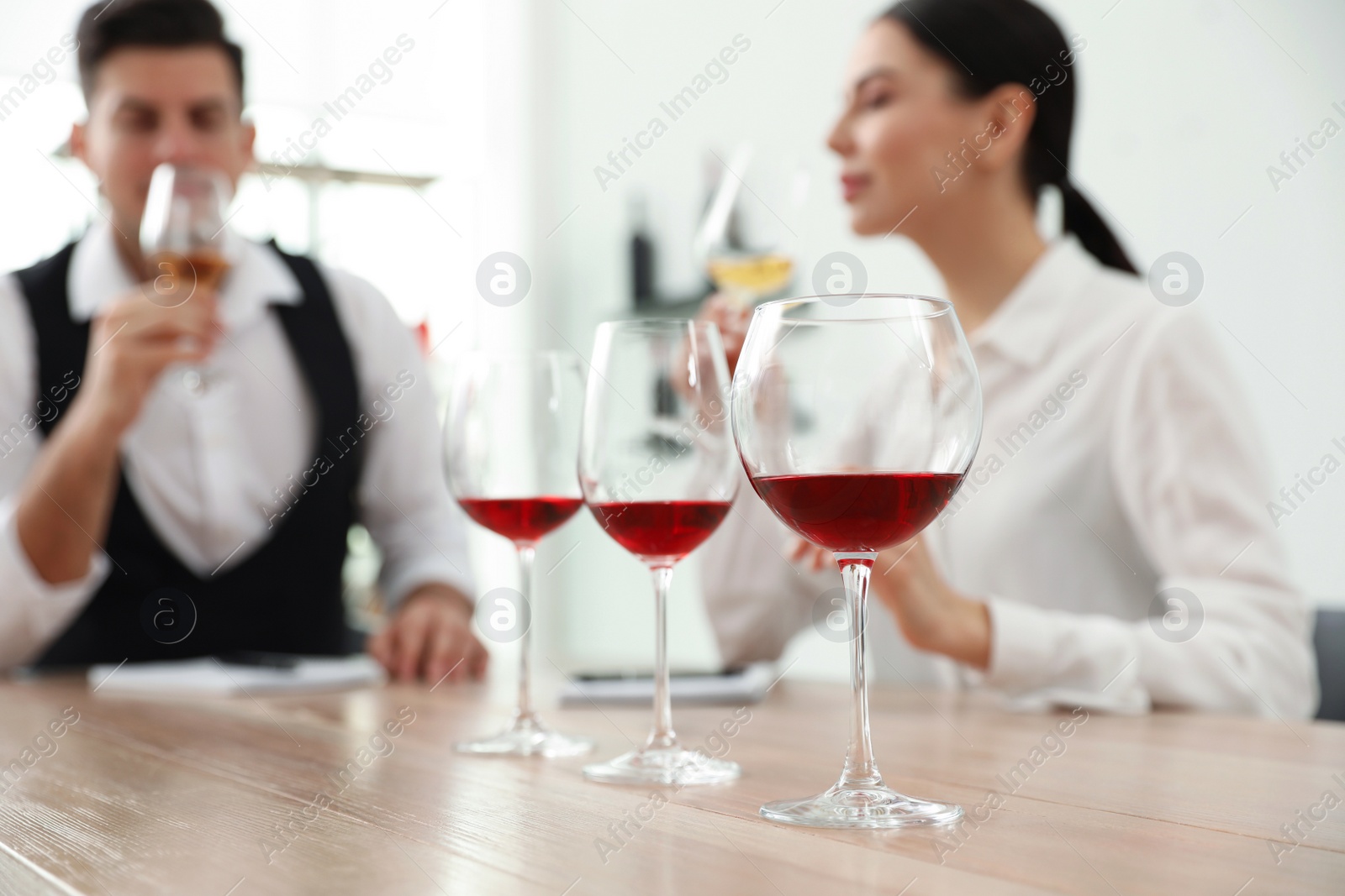 Photo of Sommeliers tasting different sorts of wine at table indoors