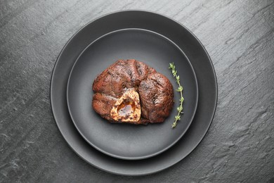 Photo of Tasty grilled beef meat and thyme on black table, top view
