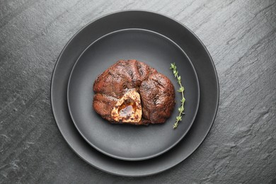 Tasty grilled beef meat and thyme on black table, top view