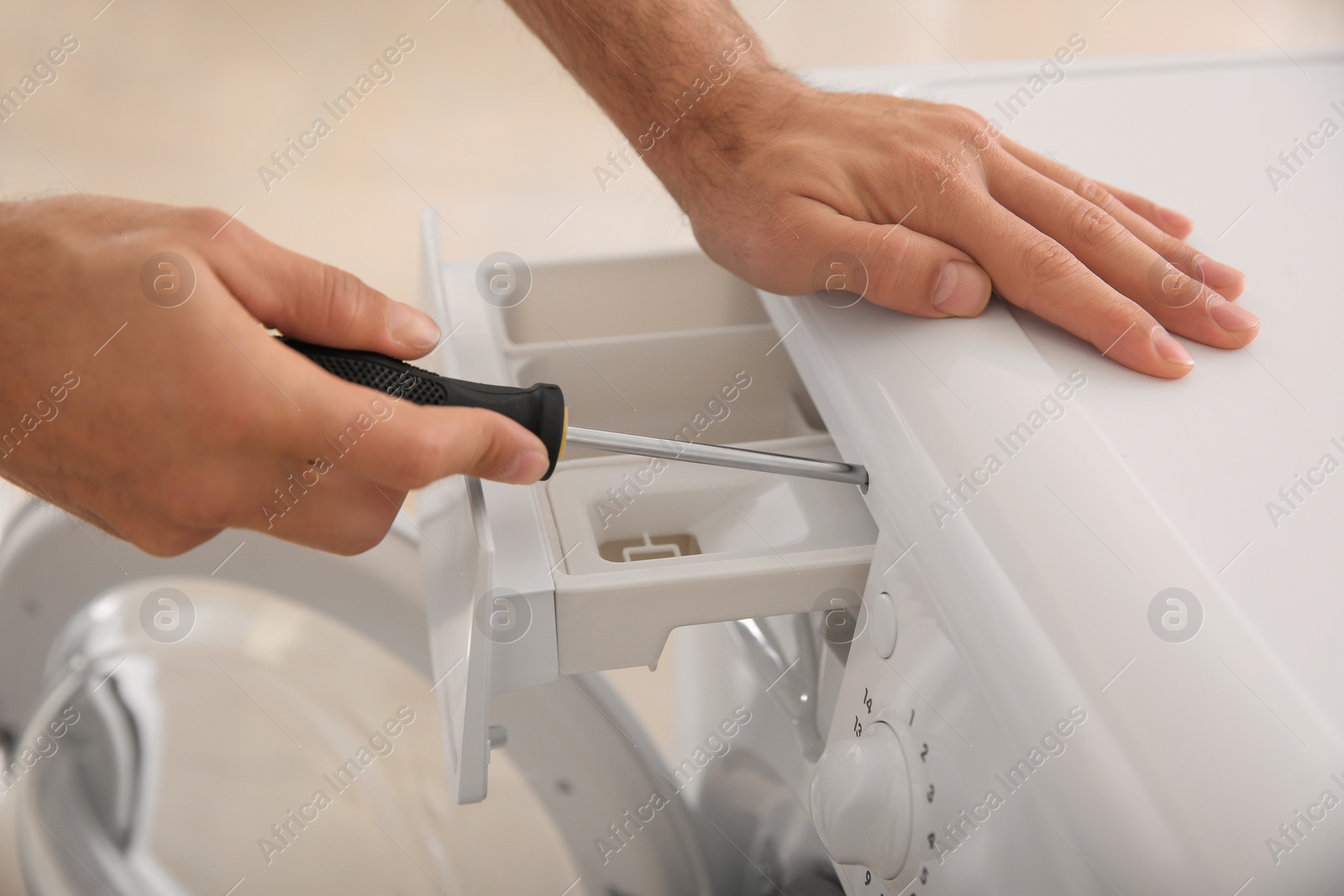 Photo of Professional plumber repairing broken washing machine, closeup