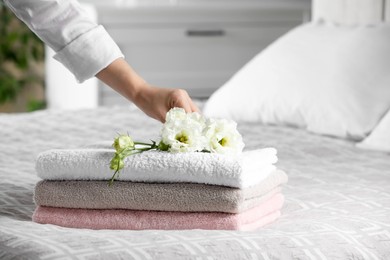 Photo of Woman putting beautiful flowers on soft towels indoors, closeup