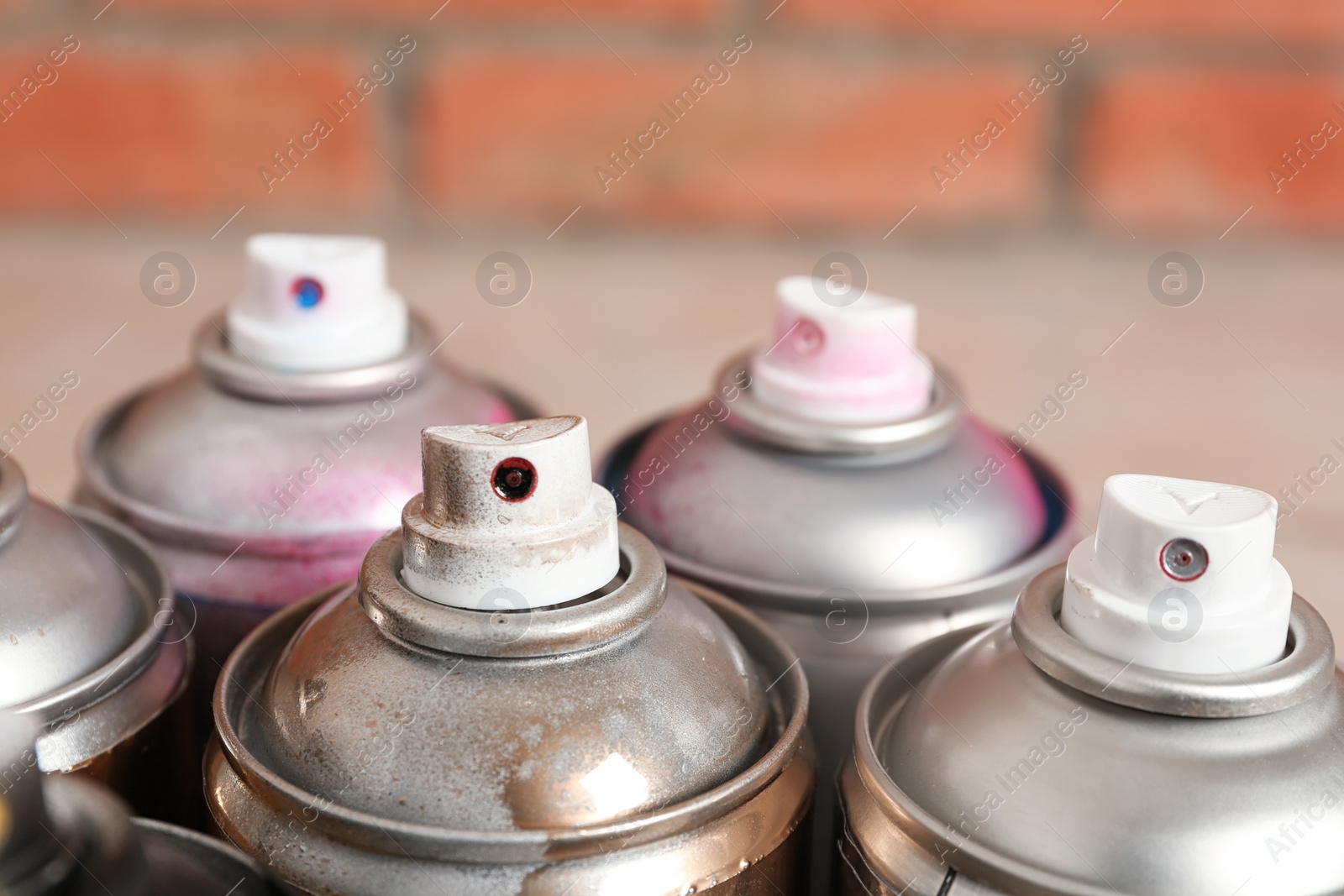 Photo of Used cans of spray paint on blurred background, closeup view